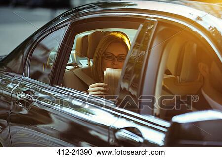Businesswoman reading newspaper in back seat of car View Large Photo Image Stock Image - Businesswoman reading newspaper in back seat of car. Fotosearch