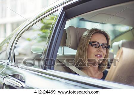 Businesswoman reading newspaper in back seat of car View Large Photo Image Stock Photo - Businesswoman reading newspaper in back seat of car. Fotosearch