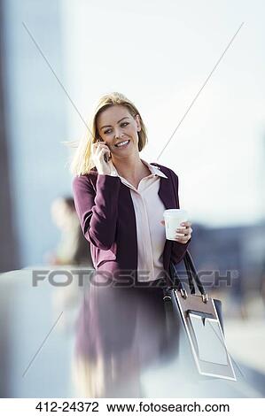Businesswoman talking on cell phone in city View Large Photo Image Stock Image - Businesswoman talking on cell phone in city. Fotosearch