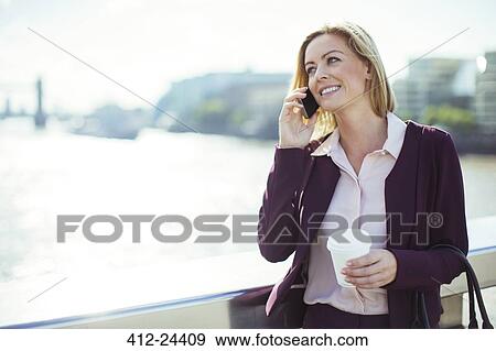 Businesswoman talking on cell phone on urban bridge View Large Photo Image Stock Photo - Businesswoman talking on cell phone on urban bridge. Fotosearch