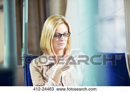 Stock Image - Businesswoman using cell phone on train. Fotosearch