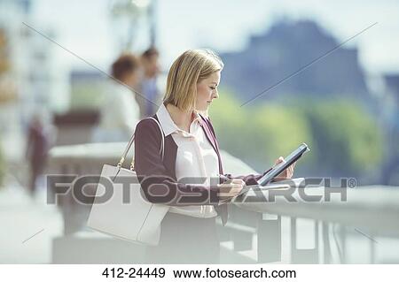 Stock Photo - Businesswoman using digital tablet at urban waterfront. Fotosearch