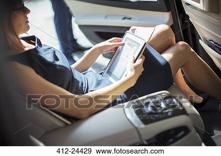 Businesswoman using digital tablet in back seat of car View Large Photo Image Stock Photo - Businesswoman using digital tablet in back seat of car. Fotosearch