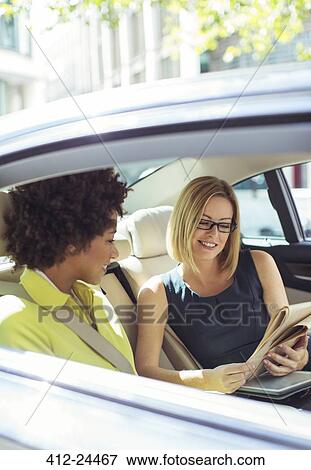 Businesswomen reading newspaper in car back seat View Large Photo Image Stock Photo - Businesswomen reading newspaper in car back seat. Fotosearch