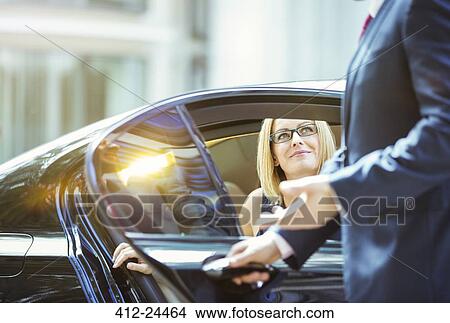Picture - Chauffeur opening car door for businesswoman. Fotosearch