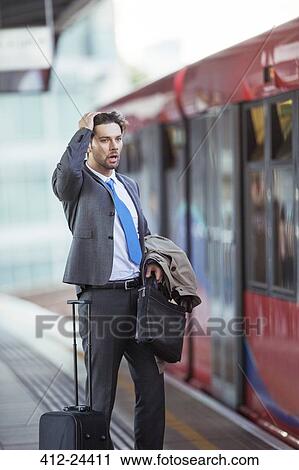 Stock Image - Frustrated businessman missing train in train station. Fotosearch