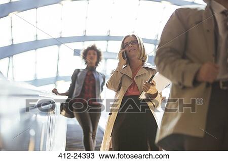Low angle view of business people riding escalator View Large Photo Image Stock Image - Low angle view of business people riding escalator. Fotosearch