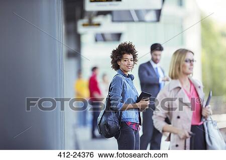 Stock Photograph - Woman holding digital tablet and waiting for train in station. Fotosearch