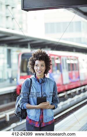 Woman holding digital tablet in train station View Large Photo Image Stock Photo - Woman holding digital tablet in train station. Fotosearch