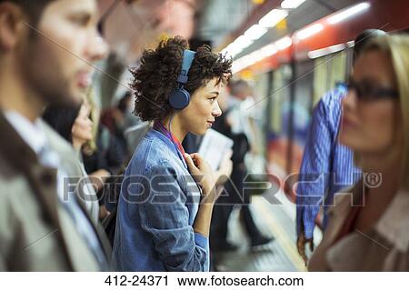 Woman listening to headphones in train station View Large Photo Image Stock Image - Woman listening to headphones in train station. Fotosearch