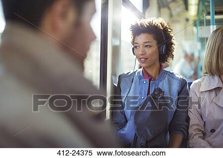 Stock Photography - Woman listening to headphones on train. Fotosearch