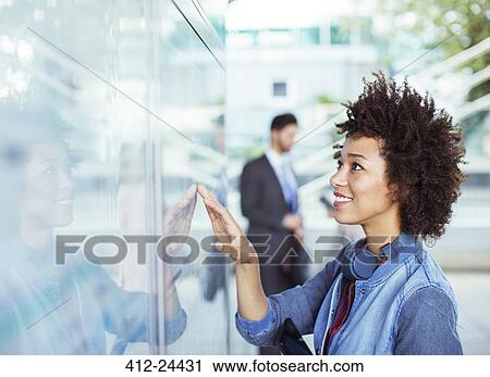 Stock Image - Woman reading transportation schedule at station. Fotosearch
