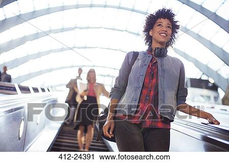Stock Image - Woman riding escalator. Fotosearch