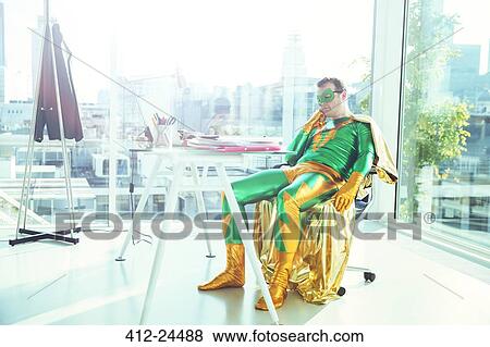 Bored superhero slouching at desk in office View Large Photo Image Stock Photo - Bored superhero slouching at desk in office. Fotosearch