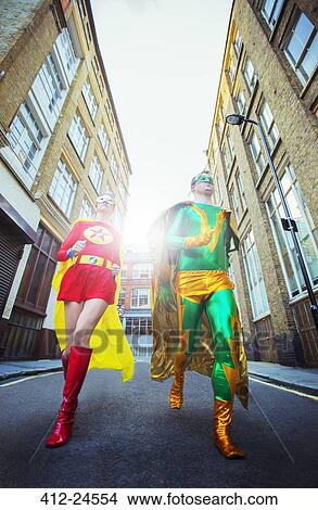 Picture - Low angle view of superhero couple running on city street. Fotosearch