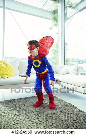 Stock Image - Superhero boy playing in living room. Fotosearch