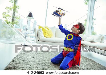 Superhero boy playing with toy helicopter in living room View Large Photo Image Stock Image - Superhero boy playing with toy helicopter in living room. Fotosearch