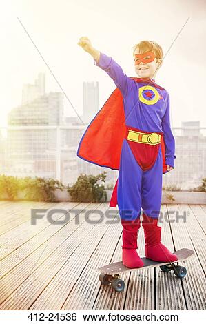 Superhero boy standing on skateboard on city rooftop View Large Photo Image Stock Photograph - Superhero boy standing on skateboard on city rooftop. Fotosearch