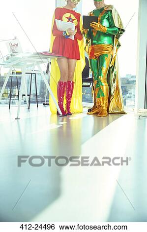 Superhero business people reading digital tablet in office View Large Photo Image Stock Photograph - Superhero business people reading digital tablet in office. Fotosearch