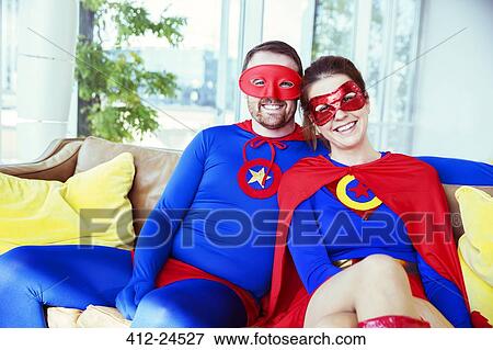 Stock Photo - Superhero couple smiling on living room sofa. Fotosearch