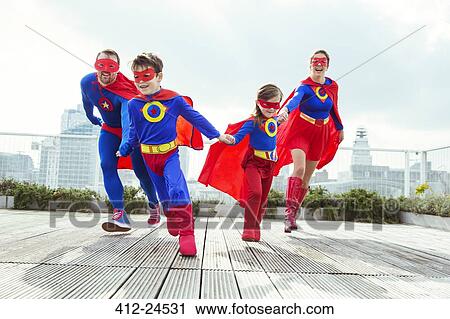 Stock Image - Superhero family playing on city rooftop. Fotosearch