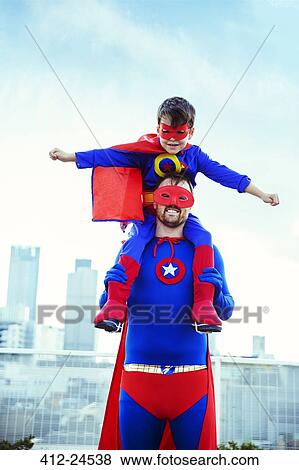 Stock Photo - Superhero father carrying son on shoulders on city rooftop. Fotosearch