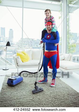Stock Image - Superhero father vacuuming and carrying daughter on shoulders. Fotosearch