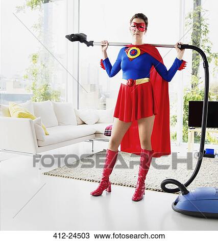 Superhero holding vacuum in living room View Large Photo Image Stock Image - Superhero holding vacuum in living room. Fotosearch