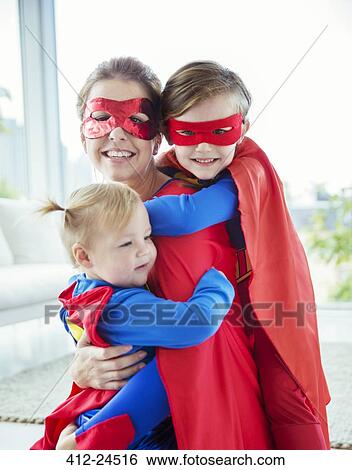 Stock Photograph - Superhero mother and children hugging in living room. Fotosearch