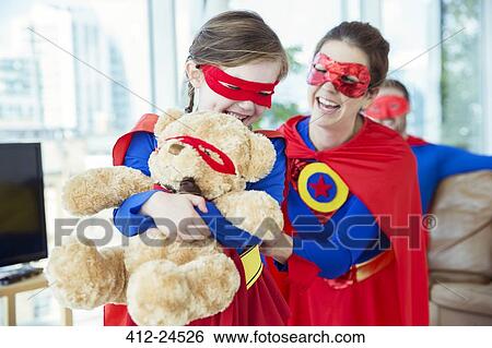 Stock Photograph - Superhero mother and daughter playing with teddy bear. Fotosearch