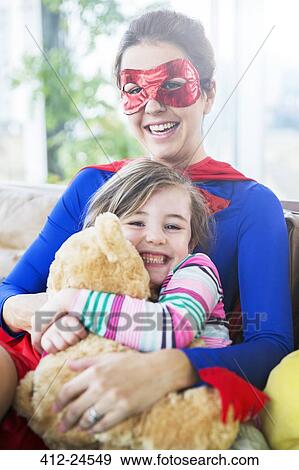 Superhero mother hugging daughter on sofa View Large Photo Image Stock Photo - Superhero mother hugging daughter on sofa. Fotosearch