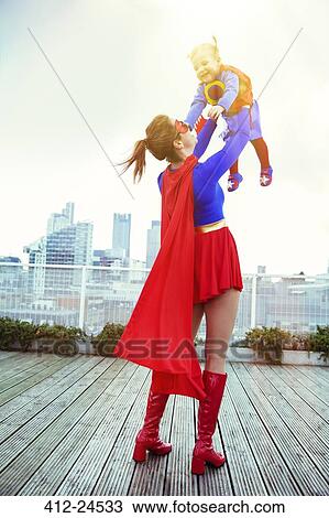 Superhero mother playing with daughter on city rooftop View Large Photo Image Stock Image - Superhero mother playing with daughter on city rooftop. Fotosearch