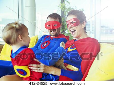 Superhero parents playing with daughter on living room sofa View Large Photo Image Stock Photography - Superhero parents playing with daughter on living room sofa. Fotosearch