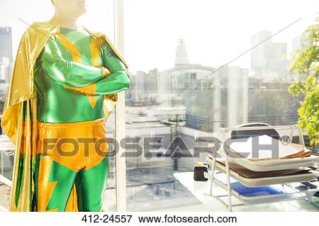Superhero standing near office desk View Large Photo Image Stock Photo - Superhero standing near office desk. Fotosearch