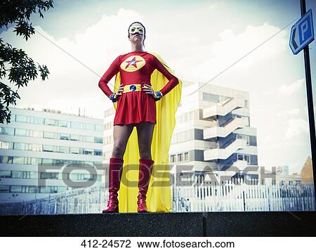 Stock Image - Superhero standing with hands on hips in city. Fotosearch