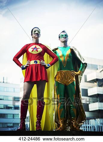 Stock Photograph - Superheroes standing on city rooftop. Fotosearch