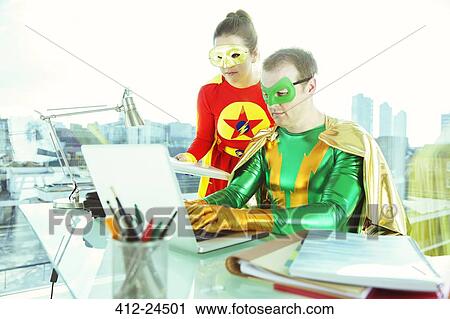 Stock Image - Superheroes working with laptop in office. Fotosearch