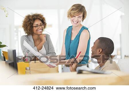 "Colleagues talking and smiling in office, holding documents" View Large Photo Image Picture - "Colleagues talking and smiling in office, holding documents". Fotosearch