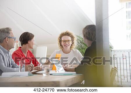 Stock Image - Four people at meeting in office. Fotosearch