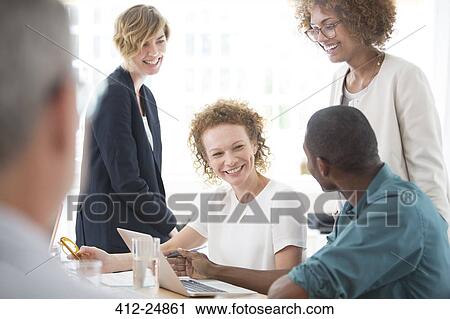 Group of office workers talking at desk View Large Photo Image Stock Image - Group of office workers talking at desk. Fotosearch