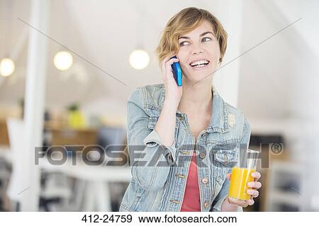 Office worker talking on phone and holding glass of juice View Large Photo Image Stock Photo - Office worker talking on phone and holding glass of juice. Fotosearch