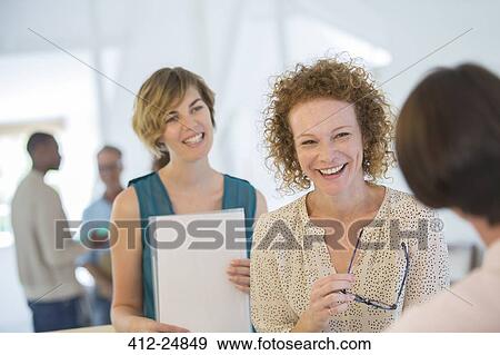 Office workers chatting and laughing during meeting View Large Photo Image Stock Photo - Office workers chatting and laughing during meeting. Fotosearch