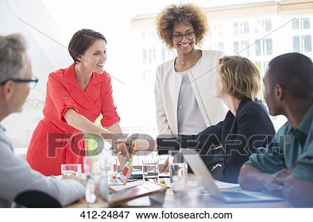 Office workers shaking hands at desk View Large Photo Image Stock Photo - Office workers shaking hands at desk. Fotosearch