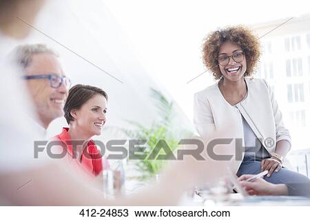 Stock Image - Office workers talking at desk. Fotosearch