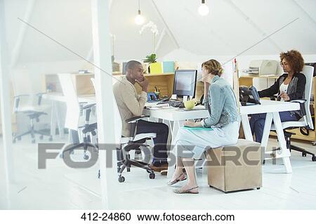 Office workers talking at desk View Large Photo Image Stock Image - Office workers talking at desk. Fotosearch