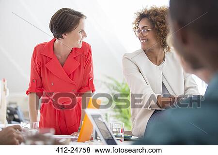 Stock Photo - Office workers talking at desk. Fotosearch