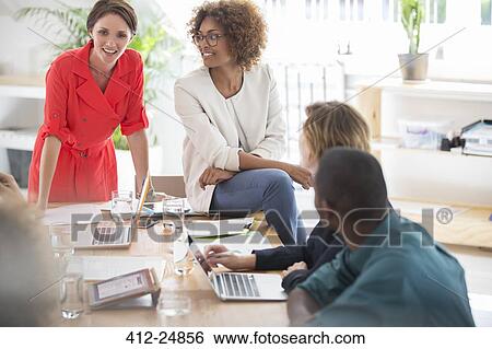 Office workers talking at desk View Large Photo Image Stock Photograph - Office workers talking at desk. Fotosearch