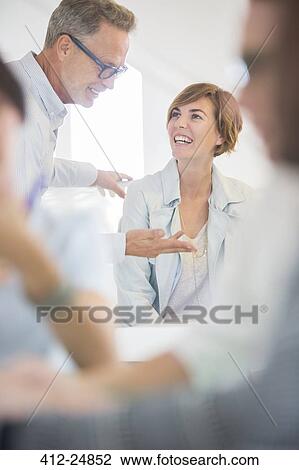 Stock Image - Office workers talking at meeting. Fotosearch