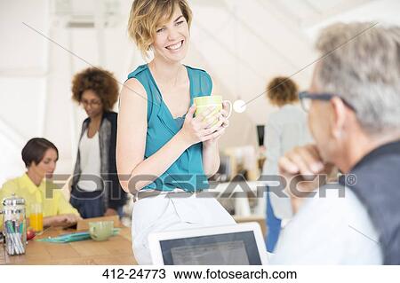 Stock Image - Office workers talking to each other during break. Fotosearch