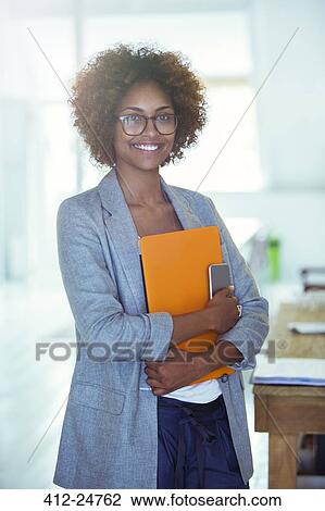 Portrait of smiling office worker holding orange file and smartphone View Large Photo Image Stock Image - Portrait of smiling office worker holding orange file and smartphone. Fotosearch